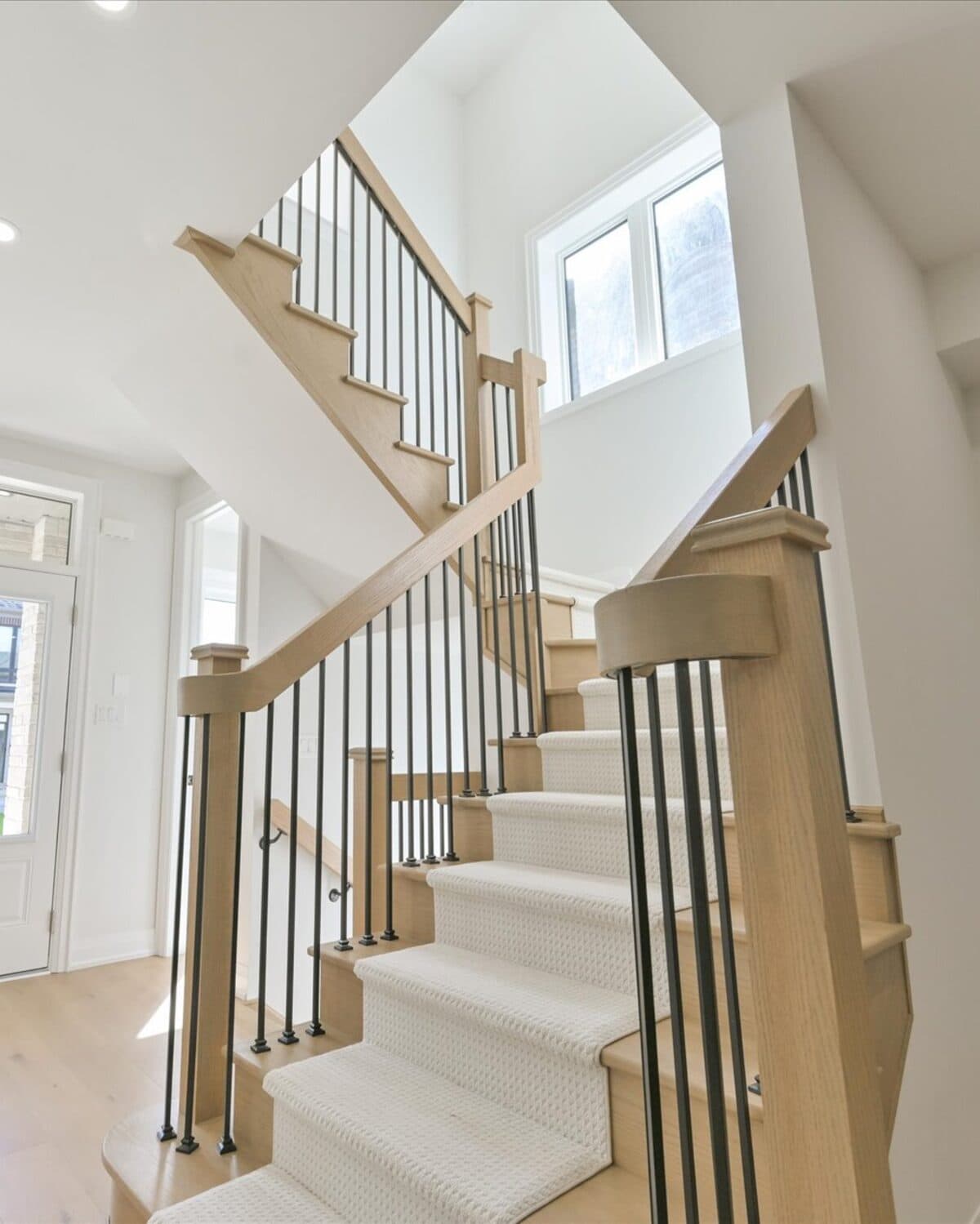 Oak-and-iron staircase rising from the front hall of a Markay home